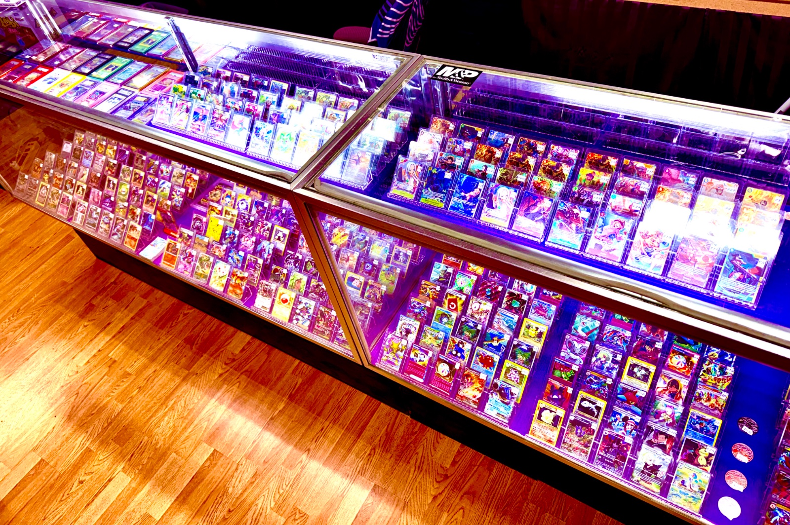Illuminated display cases filled with Pokemon cards organized in rows at Infinite Pulls card shop